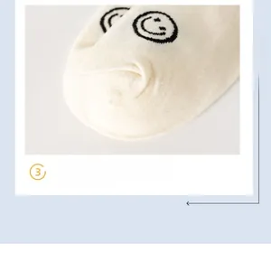 Detailed macro view of cream cotton socks featuring a black smiley face pattern on toes