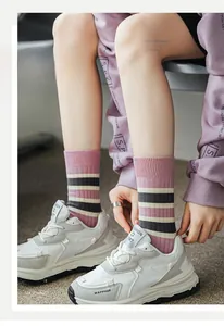 Close-up of pink and black striped mid-calf socks with ribbed cuffs on model with sneakers