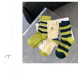 Details von grünen und beigen Baumwollsocken mit vertikalen Rippen und Blumenstickerei