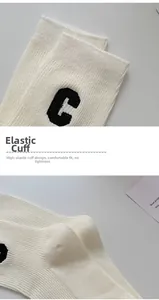 Nahaufnahme weißer Baumwoll-Sportsocken mit schwarzer 'C' Logo-Stickerei am Bündchen