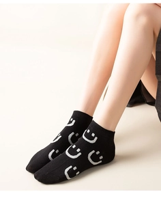 Close-up of black low-cut socks with grey smiling face pattern and ribbed cuffs