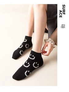 Detail of black ankle socks with grey smiley faces and breathable knitted texture