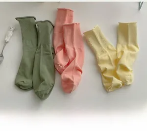 Dettaglio delle calze in cotone pastello con bordi arrotolati e trama a maglia fine