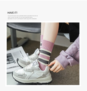 Detail view of pink and grey striped cotton crew socks paired with white sneakers