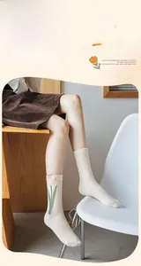 Détail de chaussette en coton peigné avec broderie tulipe rose en blanc crème