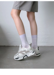 Detail of purple striped mid-calf socks paired with beige chunky platform sneakers