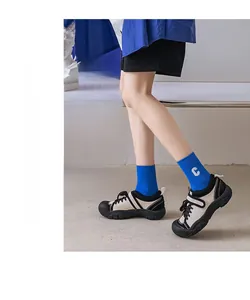 Details von blauen Baumwollsocken mit weißer C-Stickerei und kontrastreichen Freizeitschuhen