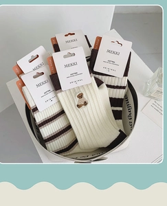 Detailed close-up of brown striped and bear embroidery cotton socks in a white basket
