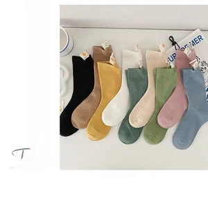 Detailed view of rib-knit crew socks with cute smiley face woven labels in eight colors