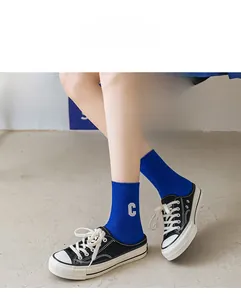 Detail der blauen Crew-Socken mit weißer C-Stickerei und vertikalem Strickmuster