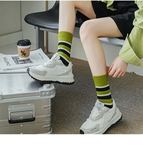 Detail von grün-schwarz gestreiften Baumwollsocken mit Retro-Sportschuhen für Damen
