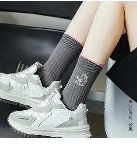 Detail of grey ribbed cotton socks with pink trim and cute squirrel embroidery
