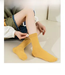 Detail of yellow ribbed knit mid-calf socks featuring a cute smiley face woven label