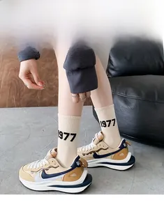 Detailed shot of beige crew socks with black 1977 text paired with retro sneakers
