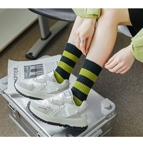 Detail von grün gestreiften Crew-Socken mit weißen Plateauschuhen auf Metallbox