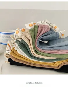Detail of colorful ribbed cotton socks featuring a white smile logo label in seven colors