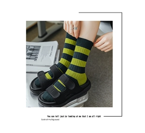 Detail von grün gestreiften Baumwollsocken kombiniert mit schwarzen Plateausandalen im Look