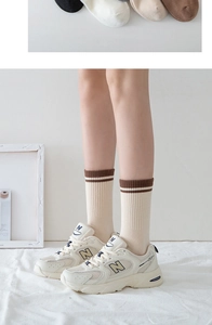 Detailed macro view of cream rib-knit mid-tube socks with brown double-stripe cuffs