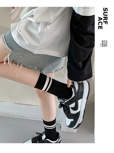 Detail of black mid-calf socks with white stripes paired with leather sneakers