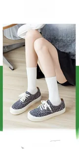 Dettaglio di sneakers in tela leopardata con lacci bianchi e calze di cotone