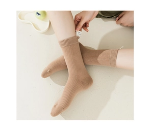 Detailed macro view of beige ribbed knit mid-calf socks with a cute smiley face tag