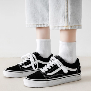 Classic black low-top sneakers with white side stripes and thick rubber soles worn with white socks