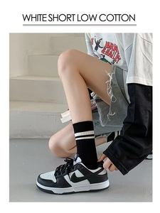 Detail of black cotton mid-tube socks with white stripes paired with sneakers