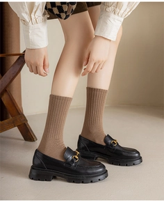 Dettaglio mocassini neri platform in pelle con morsetto dorato e calze color cammello