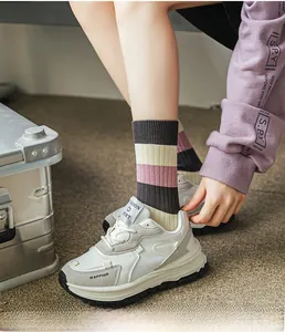Close-up of pink striped cotton crew socks worn with platform sneakers on carpet