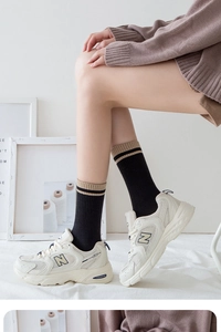 Detail of black crew socks with khaki stripes paired with mesh retro sneakers