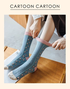 Détail d'une chaussette en coton bleu clair avec motif floral et bord-côte rose élastique