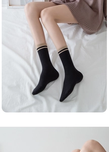 Detail of black cotton crew socks with khaki ribbed cuffs and striped trim on model