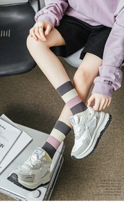 Close-up of pink and grey striped crew socks paired with thick-soled chunky sneakers