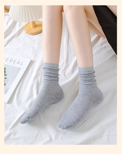 Detail of light gray ribbed cotton socks styled on a bed with a minimalist home aesthetic