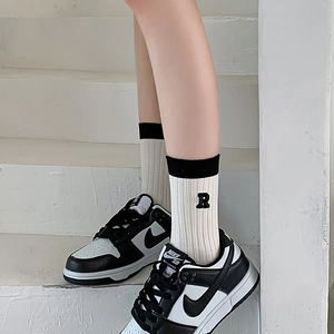 Off-white ribbed crew socks with R embroidery paired with black and white leather sneakers