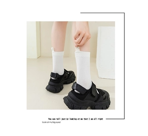 Detail of white ribbed crew socks with smile patch and black platform sneakers