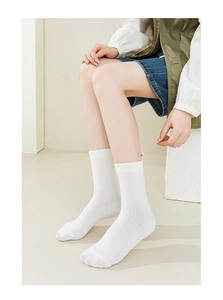 Close-up of white ribbed crew socks on model showing knit texture and calf-high fit
