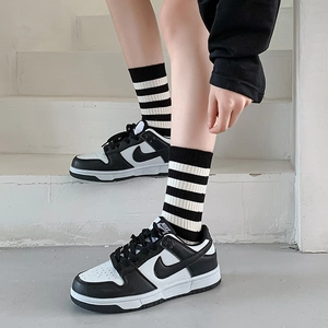 Women's black and white striped socks paired with classic leather sneakers on a stone step