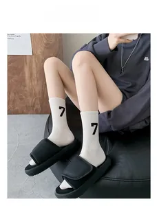 Detail of white cotton mid-calf socks with black number 7 print and platform sandals