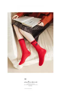 Close-up of red ribbed cotton mid-tube socks with black heart patch and space lettering