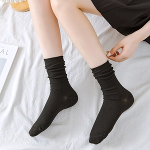 Women's black cotton crew socks with vertical knit ribbing shown in a lifestyle setting