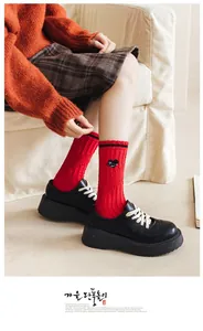 Detail of red cotton mid-calf socks with heart space embroidery and black platform shoes