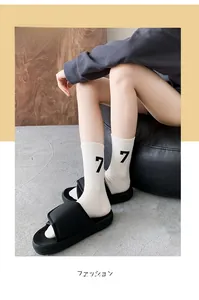 Close-up of white crew socks with black number 7 pattern worn with platform sandals