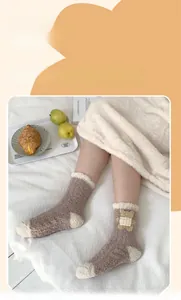 Détail de chaussettes thermiques en polaire corail avec patch ours sur lit douillet