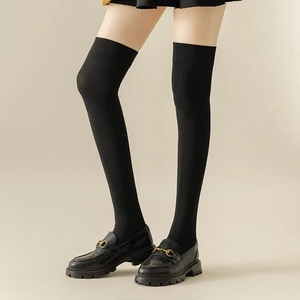 Black over-the-knee knit socks with ribbed texture paired with gold buckle loafer shoes