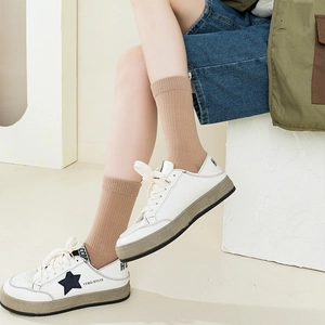 Minimalist white leather sneakers with black star and khaki ribbed crew socks for women