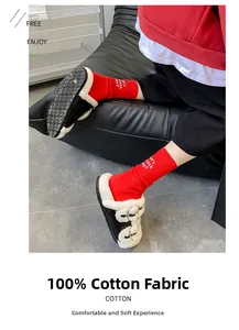 Close-up of vibrant red cotton socks paired with black fur slippers on a leather sofa