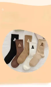 Détail de cinq paires de chaussettes en coton côtelé avec lettre A brodée en tons neutres