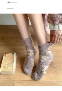 Nahaufnahme von flauschigen lila Korallenvlies-Socken mit Bärenmuster auf Holzboden