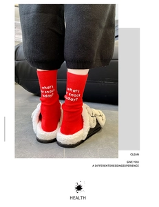 Close-up of red cotton crew socks with white snack slogan and cozy home slippers